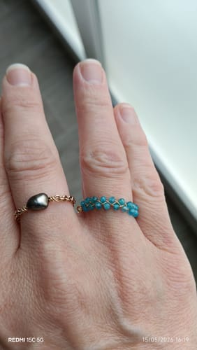 Un client montre sa main portant la bague en apatite bleue, faite de petites perles bleues tissées.