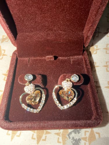 Customer's gold Mudita Earrings with sparkling crystal hearts displayed in a velvet jewelry box.