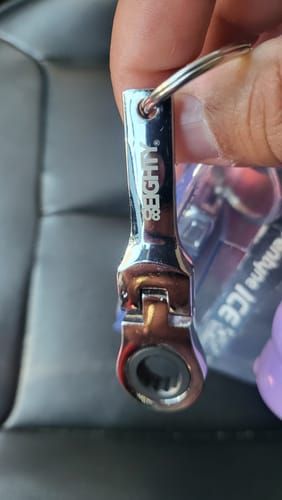 Close-up of a reviewer holding the shiny 80Eighty 10mm Wrench Keychain in their hand.
