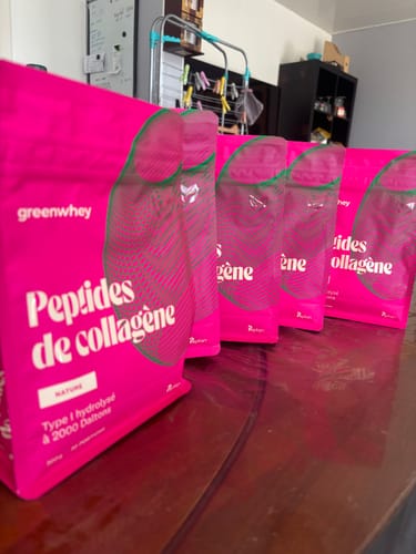 Photo d'un client montrant plusieurs sachets roses de Peptides de Collagène alignés sur une table.