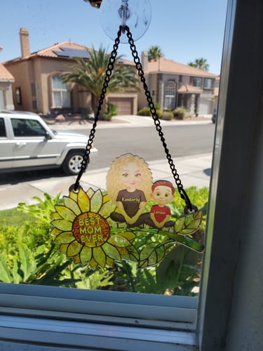Customer's personalized sunflower suncatcher with mom and child figures hanging in a sunny window.