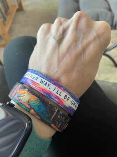 A customer's wrist with the 'Either Way, I'll Be Okay' Bracelet stacked with two other bands and a watch.