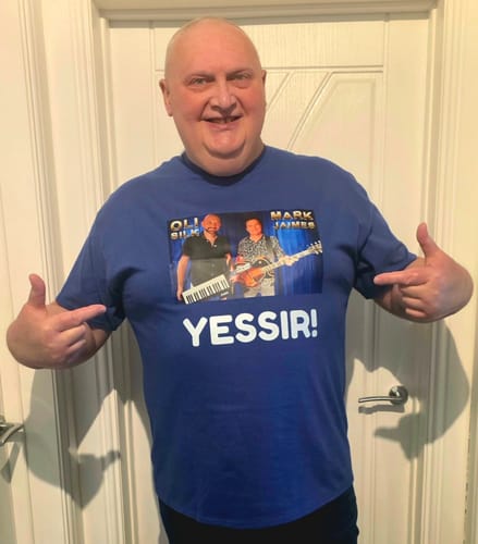 Reviewer happily pointing to their custom-printed blue unisex t-shirt.