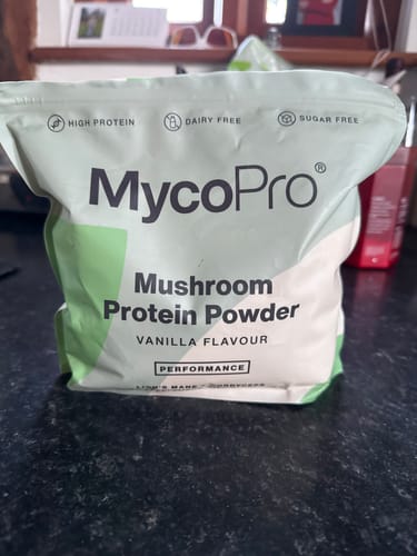 Reviewer's bag of MycoPro Mushroom Protein Powder in vanilla flavour sitting on a dark kitchen counter.