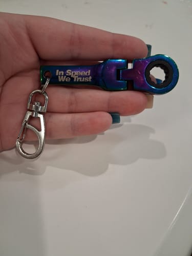 Customer holding the iridescent 10mm Wrench Keychain, which has 'In Speed We Trust' engraved on it.