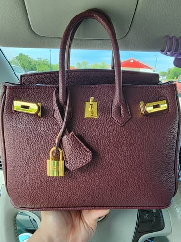 Customer holding a structured Warkin Bag in a wine color, showing its gold hardware and pebbled texture.