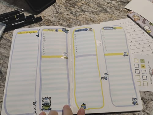 Customer showing their bullet journal's weekly spread, using colorful llama-themed stickers from their Journal Subscription.
