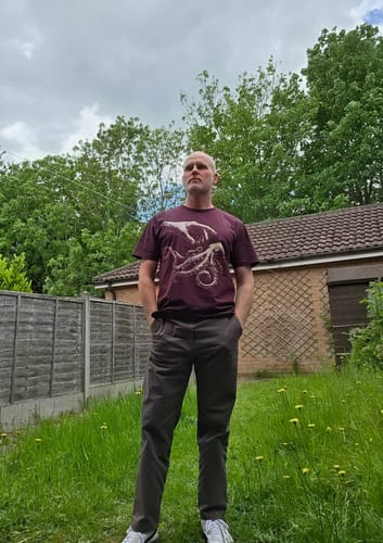 Reviewer standing outdoors wearing the burgundy Touch t-shirt, showing off the detailed graphic.