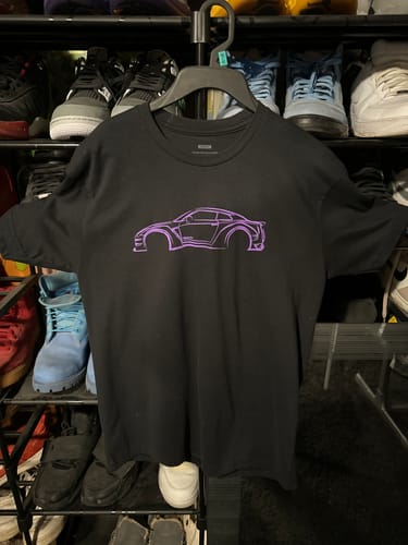 Customer's black 80Eighty® DCG88 Shirt with a purple car graphic hanging on a hanger in a closet.