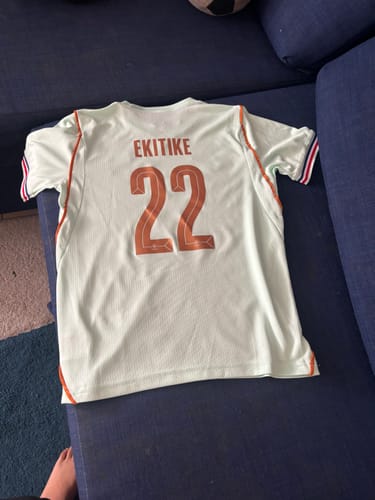 Le client montre le dos du maillot Enfant France Extérieur personnalisé avec le nom EKITIKE et le numéro 22.