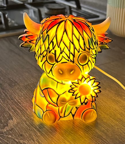Customer's Highland Cow LED Night Light glowing on a tabletop, showing its colorful stained-glass pattern.