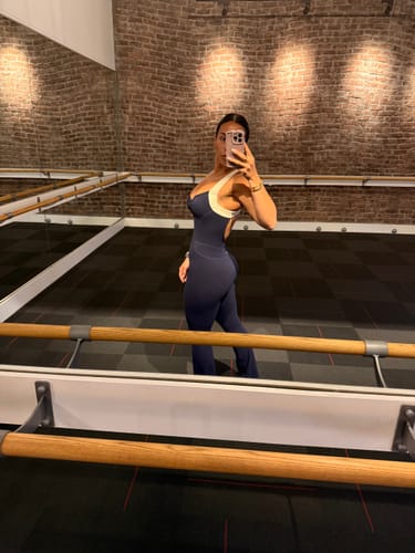 Reviewer taking a side-view mirror selfie in The Sculpt Onesie in a dance studio.
