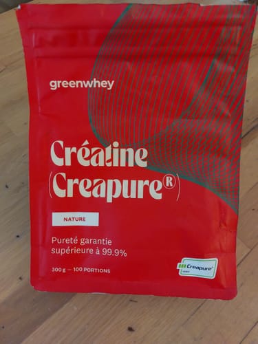 Sachet rouge de Créatine Creapure® d'un client, posé sur une table en bois.