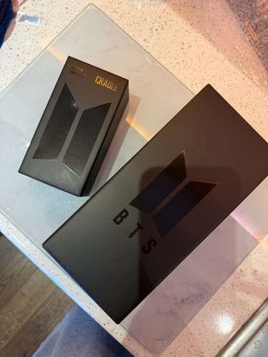 Customer's black packaging boxes for the BTS Official Light Stick Ver.4 and Cradle on a table.