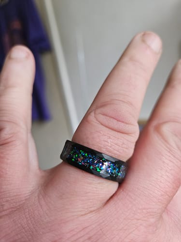 Close-up of a customer wearing the faceted black Astralis ring, showcasing its colorful crushed opal inlay.