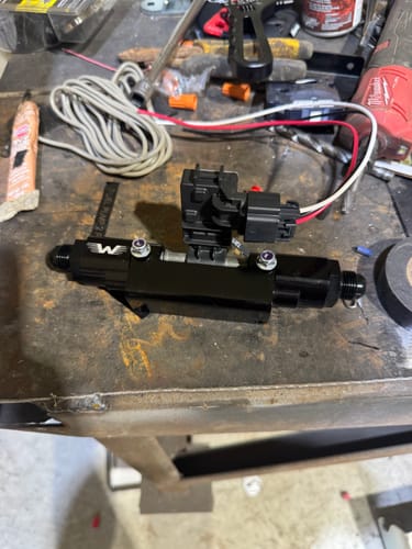 Reviewer's black Billet E85 Flex Fuel Sensor Mount with sensor installed, resting on a workbench.