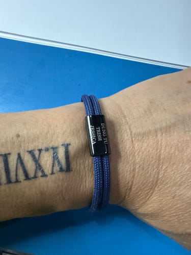 Customer wearing the blue Sail bracelet with its black engraved plate on their wrist.