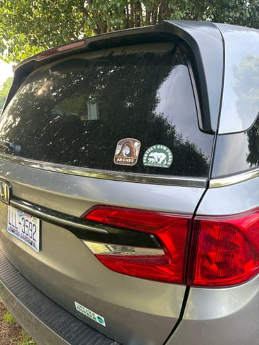 Customer's Protect Our Parks sticker on the rear window of a silver minivan, next to another park sticker.