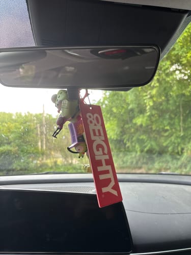 Customer's red 80Eighty Smoke Ice Air Freshener hanging from the rearview mirror of a car.