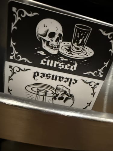 Reviewer's custom magnet with a detailed, black-and-white skull design on a metal surface.