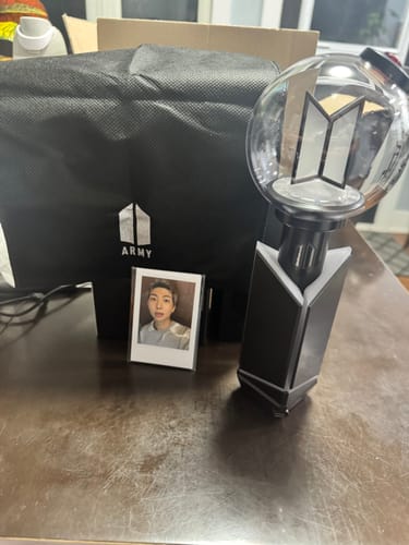 Customer's BTS Official Light Stick Ver.4 on a table with its carrying bag and a photocard.