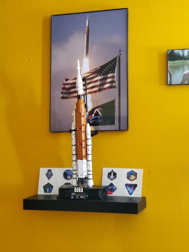 Customer's 'Four Souls, One Rocket' print hanging on a yellow wall above a shelf with a model rocket.