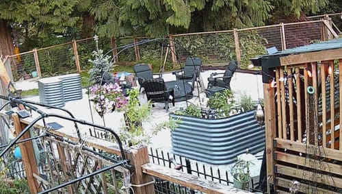 Customer's 32" Tall L-Shape steel garden bed set up on a patio and filled with plants.