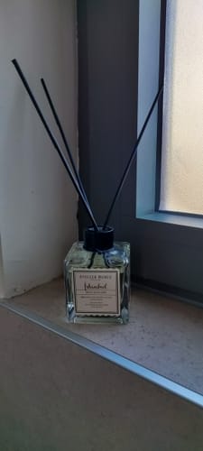 Recensent toont de Istanbul geurstokjes in een vierkante glazen fles met zwarte stokjes.