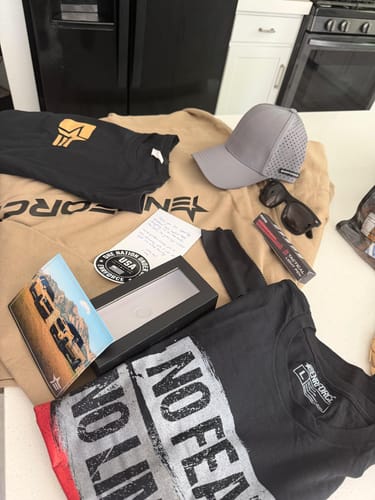 Customer's ENR#80 Exclusive Mystery Box items, including t-shirts, a hoodie, and a hat, laid out on a kitchen counter.
