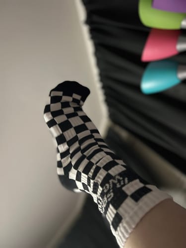 A customer's foot raised to show off the black and white CHECKERS CREW SOCKS.