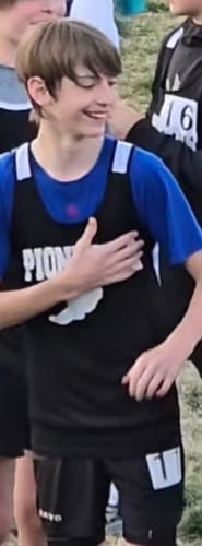 Customer wearing the black 'Strength in Christ' Youth Performance Shorts at an athletic event.