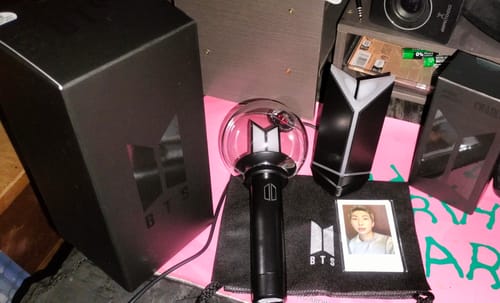 Customer's BTS Official Light Stick Ver. 4 and cradle displayed with its black packaging, pouch, and a photocard.