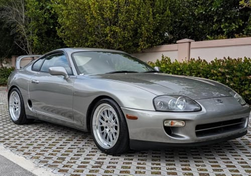 Customer's shiny silver sports car parked outdoors after being treated with Sam's Spray Wax.