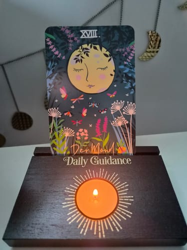 Kundenbild des Daily Guidance Kartenständers aus dunklem Holz, mit der Tarotkarte 'Der Mond' und einem brennenden Teelicht.