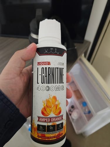 Customer holding a bottle of Amped Orange Liquid L-Carnitine 4000mg.