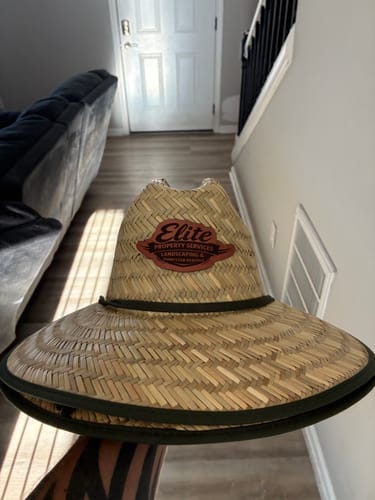 A customer holding their custom straw lifeguard hat, showing the leather patch and colored brim.