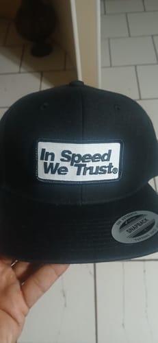 Customer holding the black Snap Back 'Tech' cap, showing the white patch on the front.