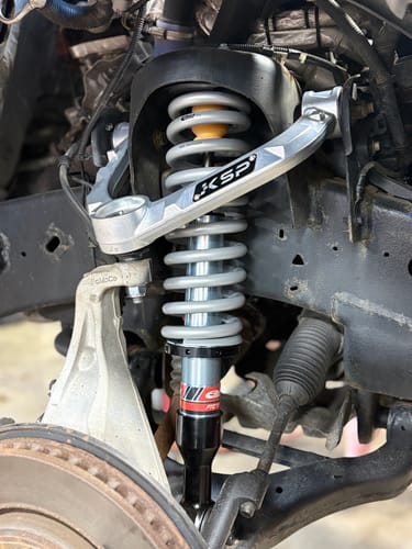 Customer's silver Forged Aluminum Upper Control Arm installed on a truck suspension system.