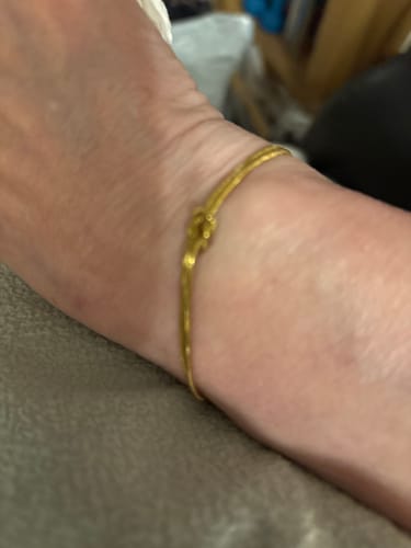 Customer's close-up of a gold knot bracelet on a wrist.