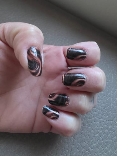 Kundin zeigt ihre manikürten Nägel mit den braun marmorierten Cappuccino Silk Marble Nagelfolien.
