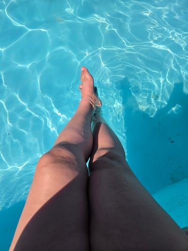 Customer relaxing with their feet in a pool, wearing the Purple Butterfly Crystal Anklet.