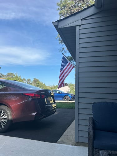 Customer's Ultra Heavy Duty American Flag hanging from a pole on their house on a sunny day.
