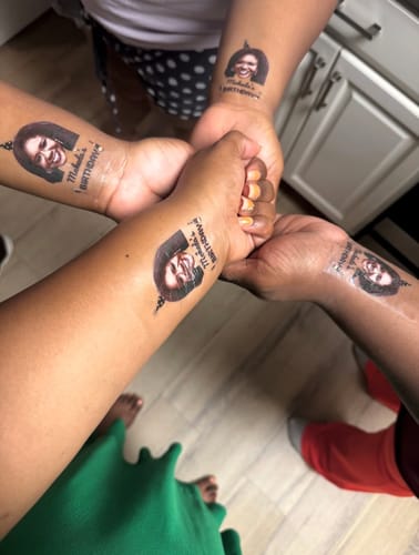 Customers holding their arms together, showing matching custom birthday tattoos on their wrists.