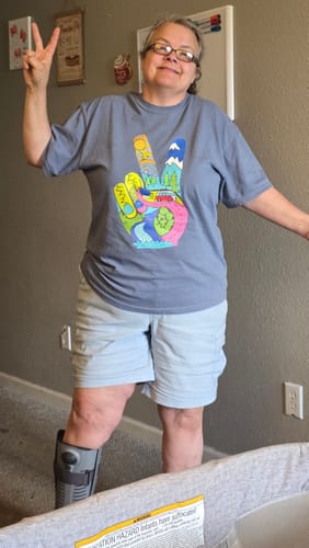 Customer smiling while wearing the grey Funky Peace T-shirt and making a peace sign.