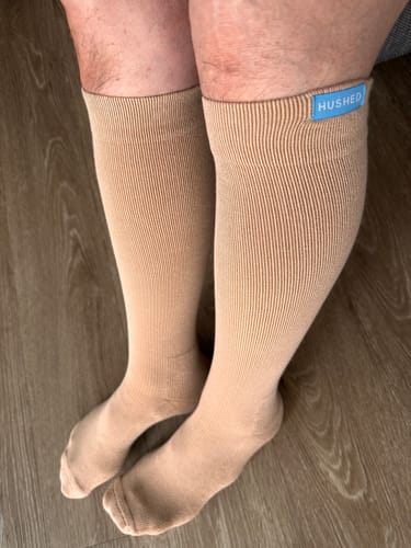 Customer wearing tan, knee-high Eucalyptus Lyocell Compression Socks indoors.