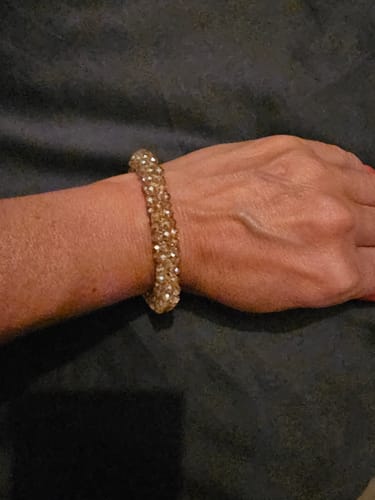 Recensent toont de Stiekie Gold kralenarmband om de pols.