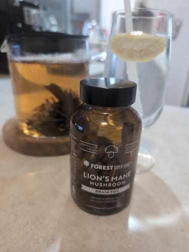 Customer's bottle of Lions Mane Mushroom Capsules on a counter as part of a morning routine with tea and lemon water.