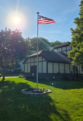 Customer's Betsy Ross Flag flying on a flagpole in their front yard on a sunny day.