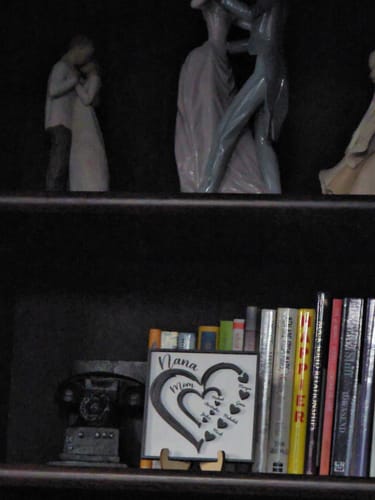 Customer's personalized Heart In Heart wooden plaque displayed on its stand on a dark bookshelf next to books.