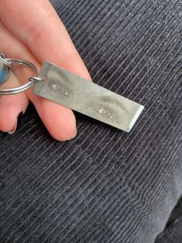 Nahaufnahme der abgenutzten Rückseitengravur auf dem Anhänger eines Rezensenten.